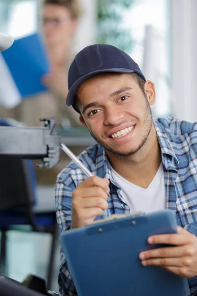 Молодий чоловік технік за офісним принтером пише на кишені — стокове фото