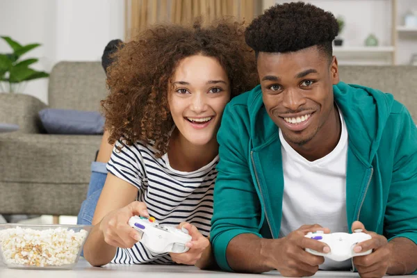 Casal feliz deitado no chão enquanto joga videogames — Fotografia de Stock