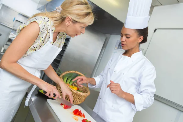 Two women are cooking fresh salad in a kitchen — Stock Photo, Image