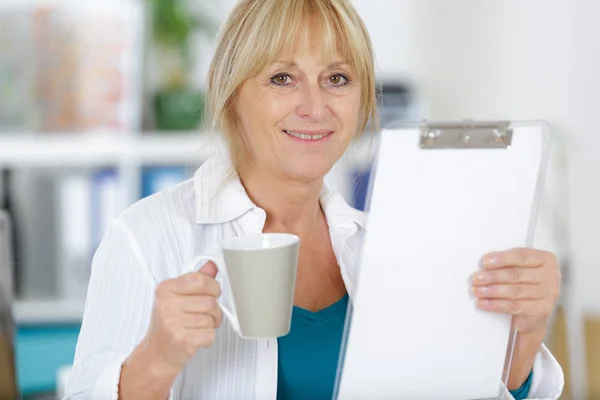 Зріла жінка приймає кавову перерву в своєму офісі — стокове фото