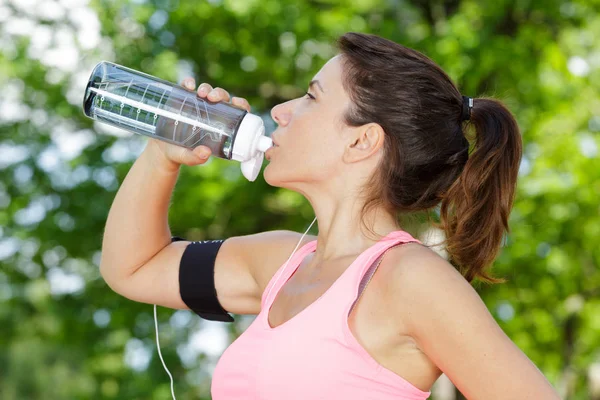 Спортивная молодая женщина пьет воду на открытом воздухе — стоковое фото