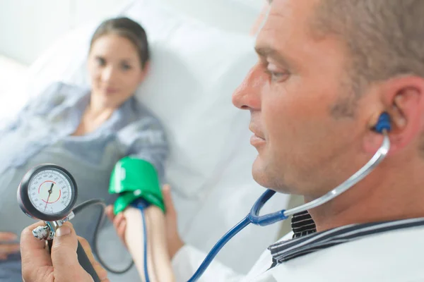 Médico verificando a pressão arterial de uma mulher grávida — Fotografia de Stock