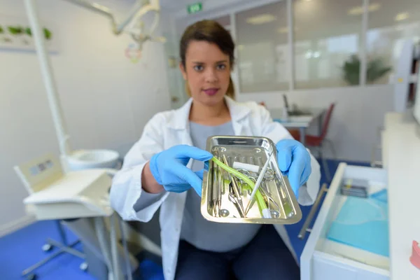 滅菌器のステンレス鋼の皿を示す歯科医 — ストック写真
