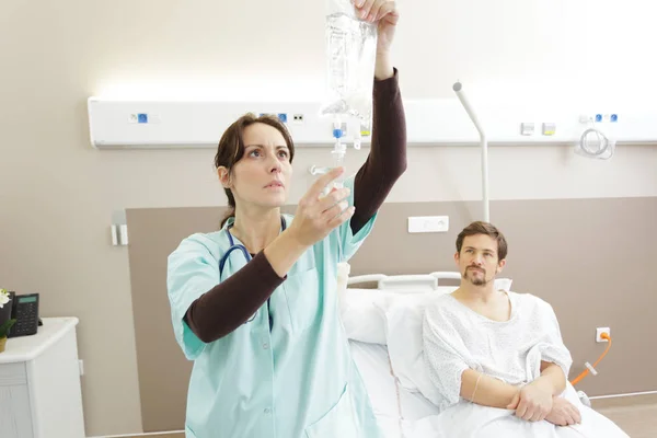 Betrokken verpleegkundige controlepatiënten infuus zak in ziekenhuis — Stockfoto