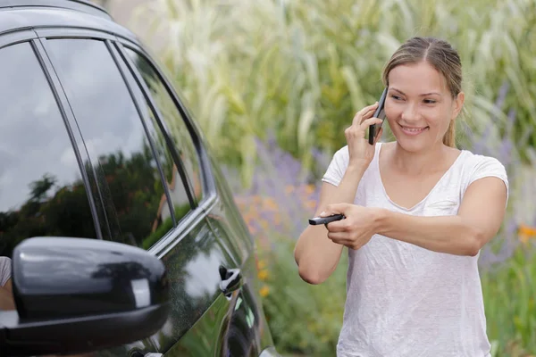 Жінка відкриває двері автомобіля під час використання телефону — стокове фото