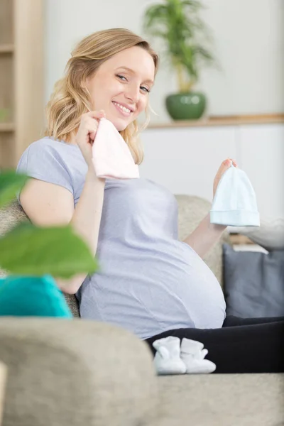 Mulher grávida feliz segurando panos de bebê por nascer — Fotografia de Stock