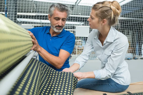 Man och kvinna att välja tyg från förvaringshyllor — Stockfoto