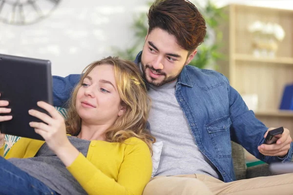 Joyeux jeune couple relaxant à la maison avec une tablette — Photo