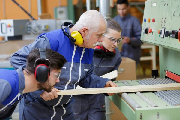 Hombre y aprendices cortando madera —  Fotos de Stock