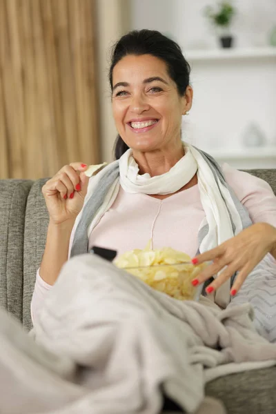 Mulher com tigela de batatas fritas assistindo tv — Fotografia de Stock