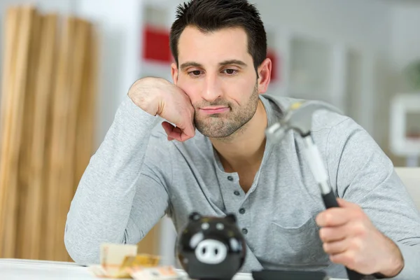 Man verdrietig om zijn spaarvarken te breken — Stockfoto