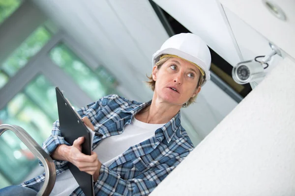 Technikerin installiert Kamera mit Schraubenzieher an Wand — Stockfoto