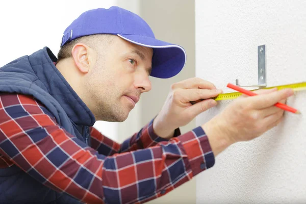 Man measures on the wall with a ruler — Stock Photo, Image