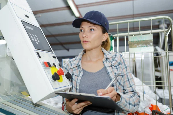 Kvinnlig tillverkningsarbetare som opererar en maskin — Stockfoto