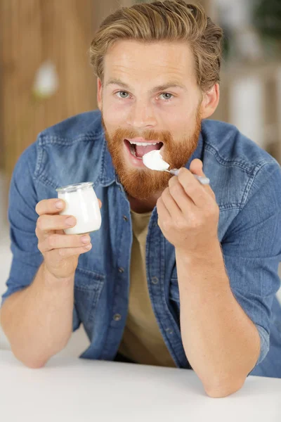 Homem jovem comendo iogurte — Fotografia de Stock