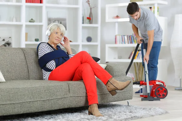 Young man home help cleaning ladys living room — ストック写真