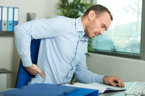 Hombre de negocios con dolor de espalda en una oficina —  Fotos de Stock