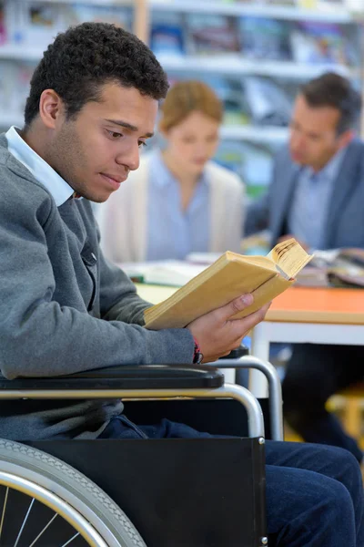Φοιτητής σε αναπηρικό καροτσάκι διαβάζοντας ένα βιβλίο — Φωτογραφία Αρχείου