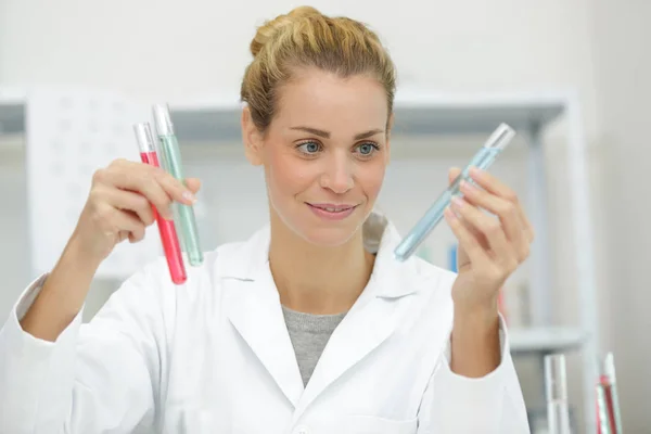 Feliz mulher médica trabalhador compara tubos de ensaio — Fotografia de Stock