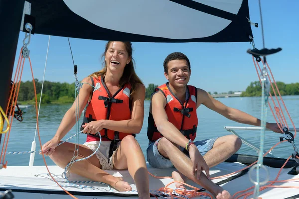 Par skrattar samtidigt som man försöker manipulera segel — Stockfoto