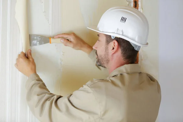 Visão traseira do construtor masculino remover papel de parede velho — Fotografia de Stock