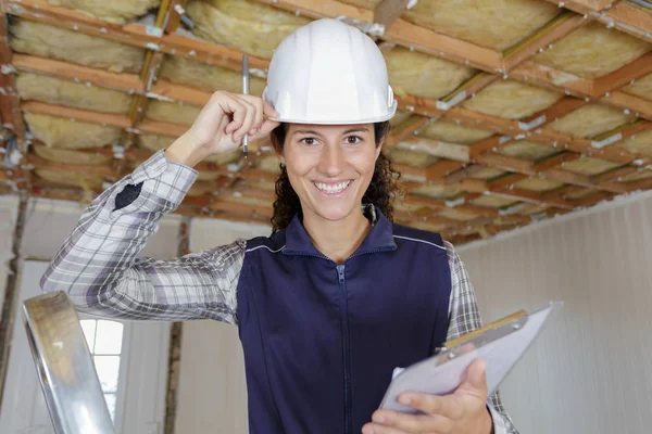 Young woman builder stands on a stepladder — ストック写真