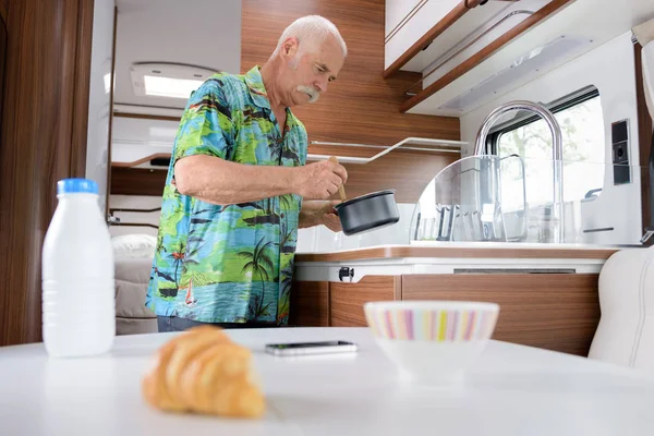 Homem idoso cozinhar dentro de sua campervan — Fotografia de Stock