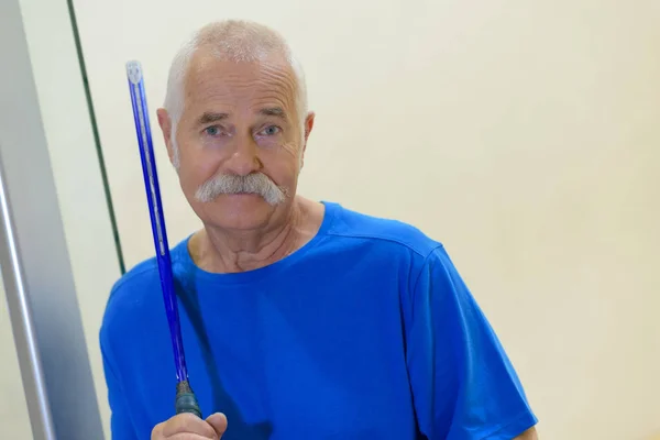 Portrait of a senior man holding a tennis racket — Stock Photo, Image