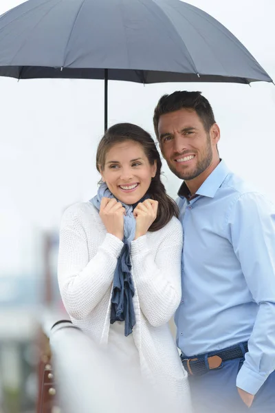 Abrigo casal atraente sob guarda-chuva — Fotografia de Stock