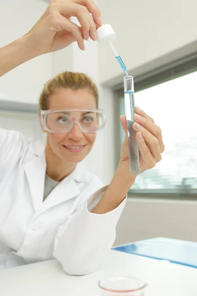 年轻的女技师在化学实验室里用长笛 — 图库照片