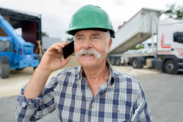 Homem sênior no capacete falando telefone celular — Fotografia de Stock