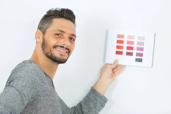 Pintor hombre con muestras de color en la mano — Foto de Stock