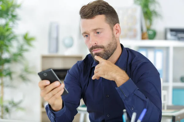 Красивий чоловік використовує свій телефон в сучасному офісі — стокове фото