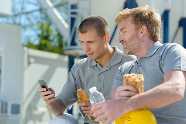 Trabajadores en la hora del almuerzo hombre más joven utilizando el teléfono inteligente —  Fotos de Stock