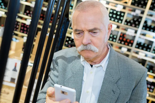 Homme utilisant son téléphone dans le magasin de vin — Photo