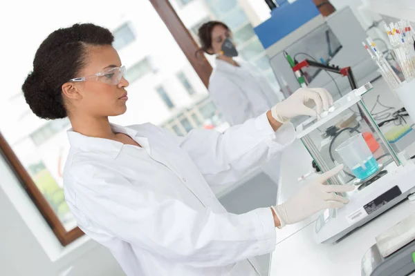 Kvinnlig labbassistent studerar blodprov för analys — Stockfoto