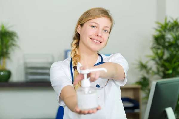 Female nurse handing hand sanitizer — Stock Photo, Image