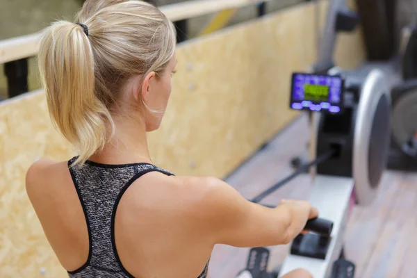 Mulher atleta exercício na máquina de remo — Fotografia de Stock