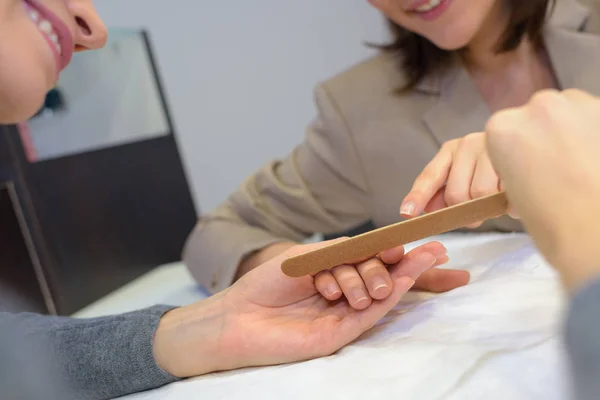 Manos de mujer con hermosas uñas y una lima de uñas — Foto de Stock