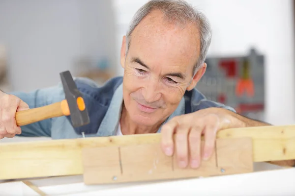 Carpinteiro homem sênior trabalhando com martelo — Fotografia de Stock