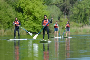 group of people stand up paddleboarding clipart