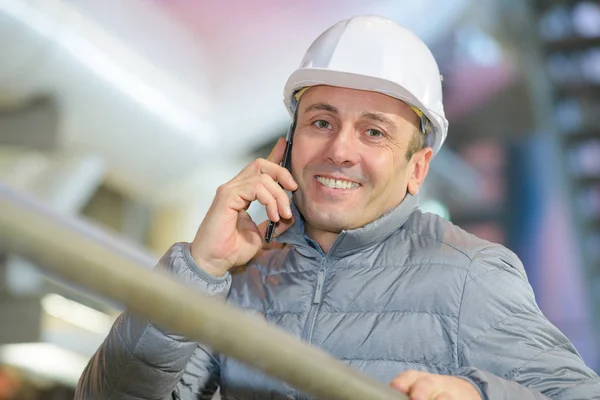 Engenheiro sorridente segurando telefone inteligente — Fotografia de Stock