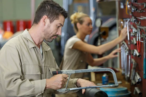 Homem corta tubos com uma serra manual — Fotografia de Stock