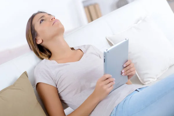 Tablet ile kanepede yatan üzgün genç kız — Stok fotoğraf