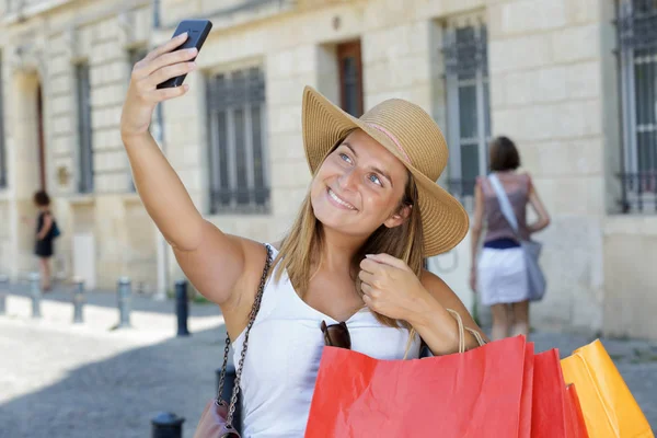 Mulher com chapéu com sacos fazendo uma selfie — Fotografia de Stock