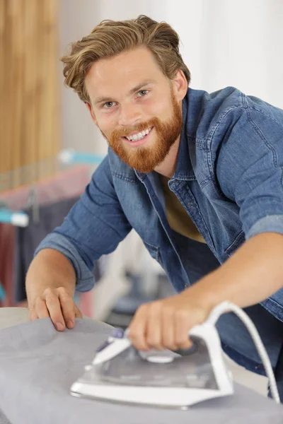 Evde demir tahta üzerinde gömlek ütü mutlu adam — Stok fotoğraf