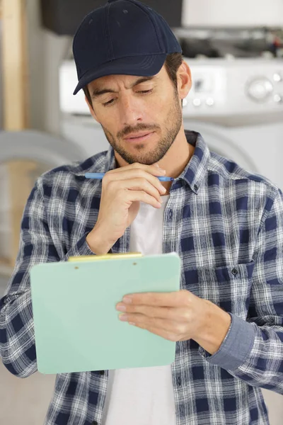 Contemplative serviceman in the home looking at clipboard — Stock Photo, Image