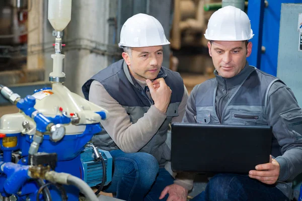 Zwei Vorarbeiter arbeiten in Fabrik mit Laptop — Stockfoto