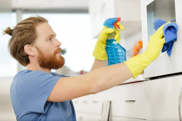 Man spraying an oven in kitchen — Stock Photo, Image