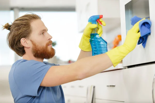 Hombre rociando un horno en la cocina — Foto de Stock